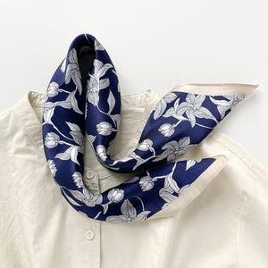 a deep blue silk bandana scarf featuring floral print with light beige edges, paired with a light beige turtleneck shirt