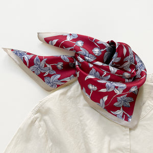 a burgundy red silk bandana scarf featuring floral print with light beige edge, tied as a triangle bib, paired with a light beige turtleneck shirt