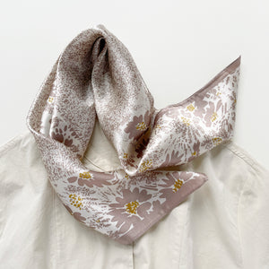 a women's pink beige floral print silk scarf on white base, paired with a turtleneck shirt