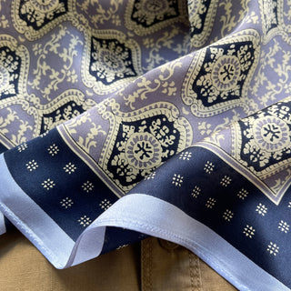 Unisex silk bandana scarf featuring a geometric floral pattern in velvet, navy, and white, with a navy border.