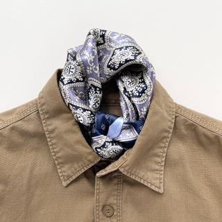 Unisex silk bandana scarf featuring a geometric floral pattern in velvet, navy, and white, with a navy border.