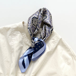 Unisex silk bandana scarf featuring a geometric floral pattern in velvet, navy, and white, with a navy border.