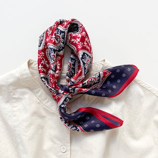 Unisex silk bandana scarf featuring a geometric floral pattern in red, navy, and white, with a navy border.