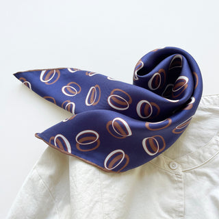 Indigo purple unisex silk bandana scarf with a circular pattern, made from 100% silk twill, featuring hand-rolled edges. The scarf measures 53x53cm and is designed for both men and women.