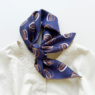 Indigo purple unisex silk bandana scarf with a circular pattern, made from 100% silk twill, featuring hand-rolled edges. The scarf measures 53x53cm and is designed for both men and women.