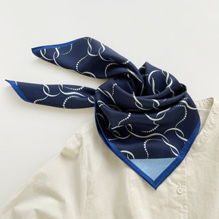 65x65 cm navy blue silk scarf with a geometric pattern and hand-rolled edges, designed for both men and women. The scarf features a smooth silk texture and is accented with elegant white wave-like lines, perfect for versatile styling.