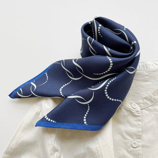 65x65 cm navy blue silk scarf with a geometric pattern and hand-rolled edges, designed for both men and women. The scarf features a smooth silk texture and is accented with elegant white wave-like lines, perfect for versatile styling.