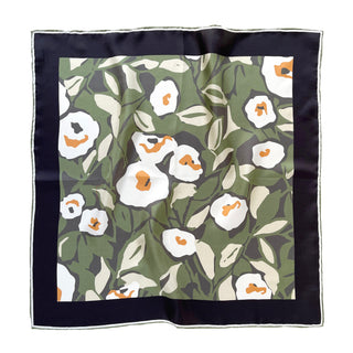 A 100% silk twill bandana with hand-rolled edges, featuring a floral design with white flowers and green leaves, framed by a black border.