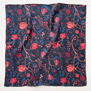 Floral silk bandana scarf with hand-rolled edges featuring a deep blue and black base adorned with intricate red and pink floral patterns. Made from 100% silk twill, the scarf measures 53x53cm, showcasing a luxurious texture and artisanal craftsmanship.