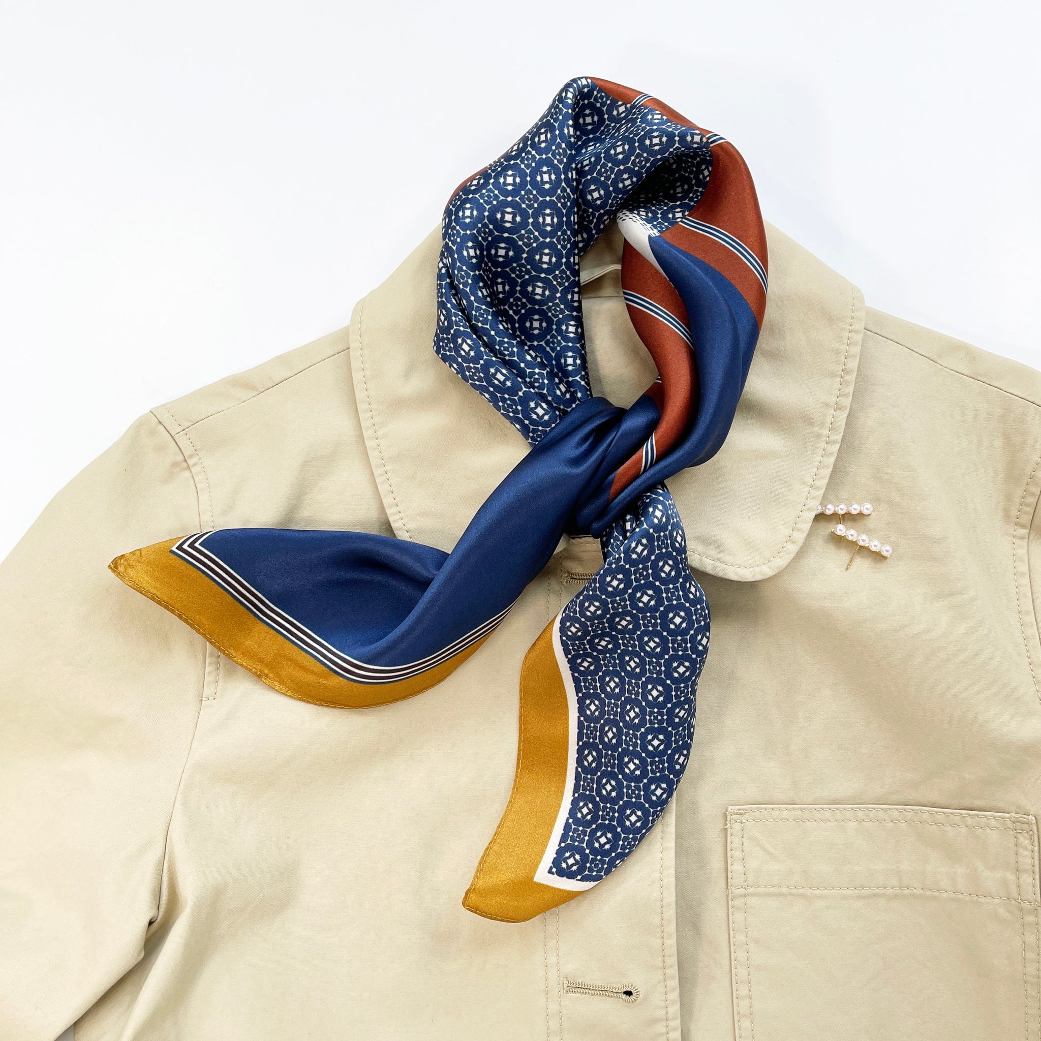 a unisex silk scarf with geometric pattern in navy blue, copper and mustard yellow