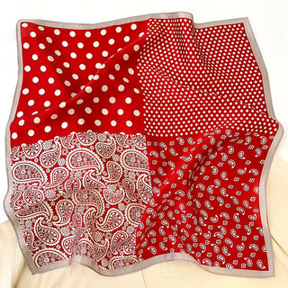 A 53x53 cm silk bandana scarf featuring a vibrant red design with alternating patterns of polka dots and classic paisley prints in white. The scarf is divided into four quadrants, each showcasing either large or small polka dots or intricate paisley motifs. A subtle grey border frames the scarf, adding a refined touch. The luxurious silk fabric has a smooth, glossy finish, making it a versatile accessory for both casual and formal wear.