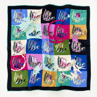 A vibrant small square silk scarf with swirling snakes print and hand-rolled hems. The swirling snakes are printed on different colour blocks such as blue, red, green, and yellow.