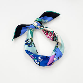 a vibrant small square silk scarf with snake print and hand-rolled hems knotted as a headband