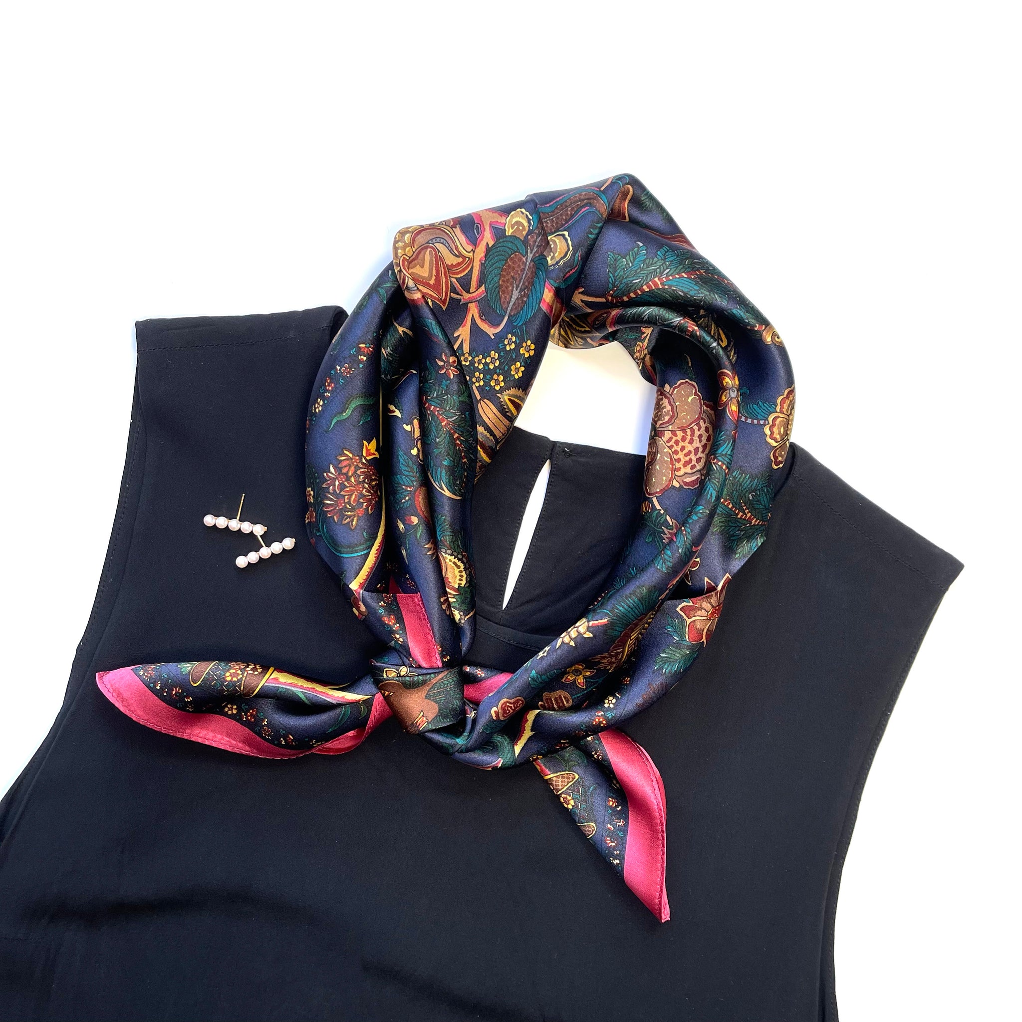 a blue vintage inspired floral printed silk scarf with magenta edge, knotted as a classic neckerchief, paired with a black sleeveless dress