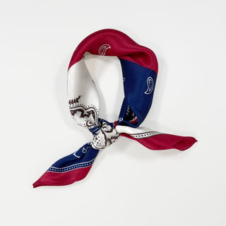 a bohemian paisley silk scarf in blue, red and white palette knotted as a neckerchief 