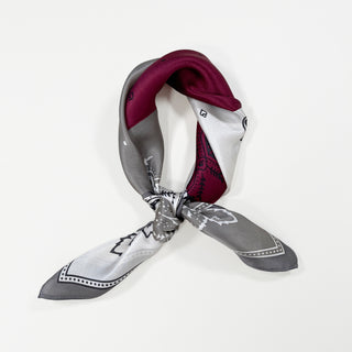 a bohemian paisley silk scarf in plum red, grey and white palette knotted as a neckerchief 