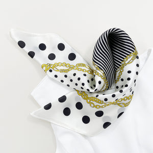 a small square silk scarf for women featuring polka dot and stripe print in white and black palette paired with a sleeveless white dress