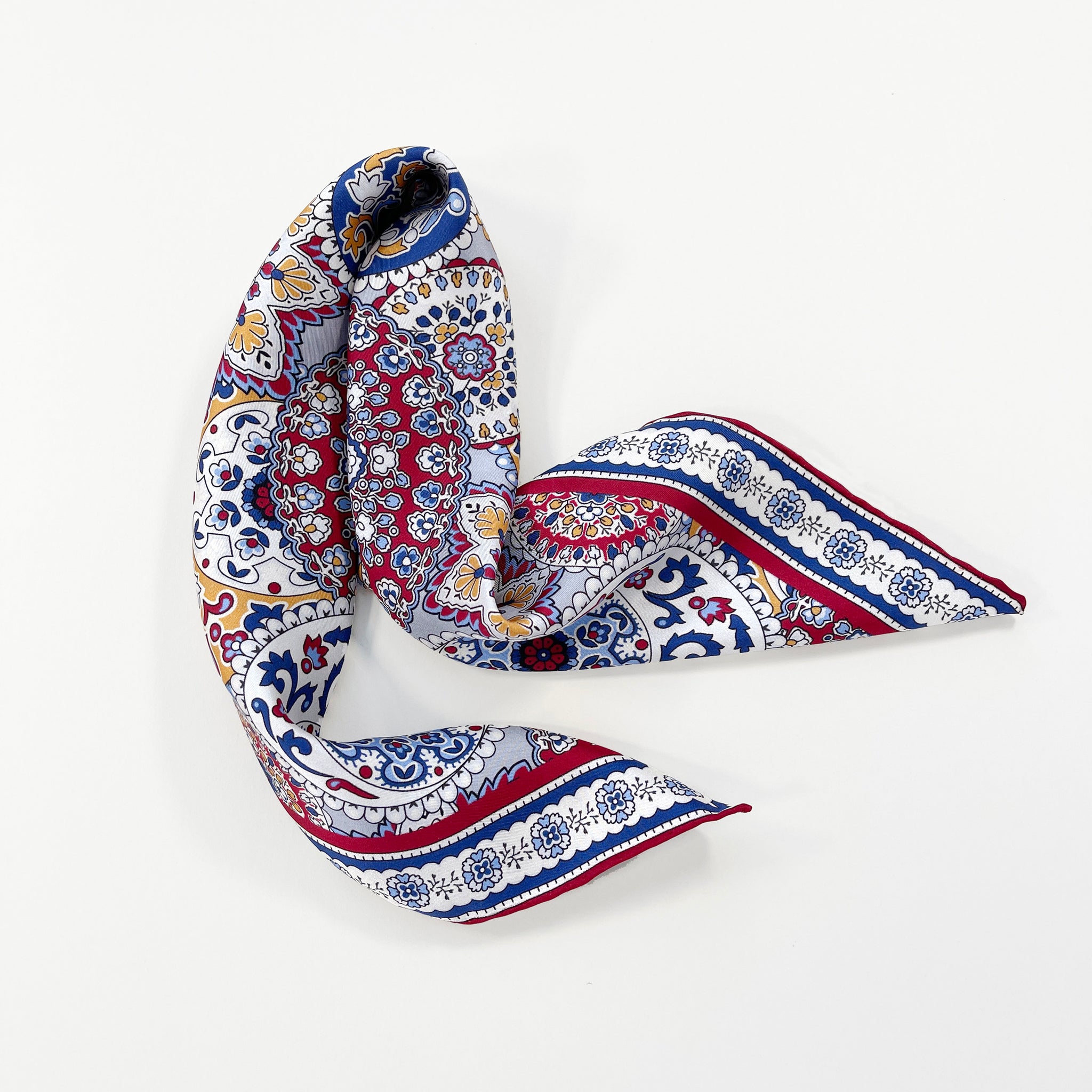 a red, blue and yellow silk scarf square for men featuring boho-style print and red hand-rolled hems