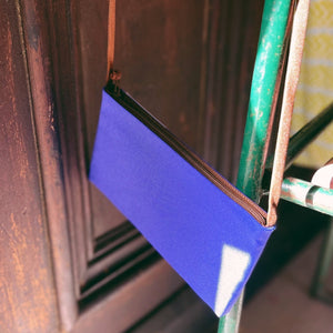 an indigo blue small crossbody phone purse with handmade button hanging on a chair