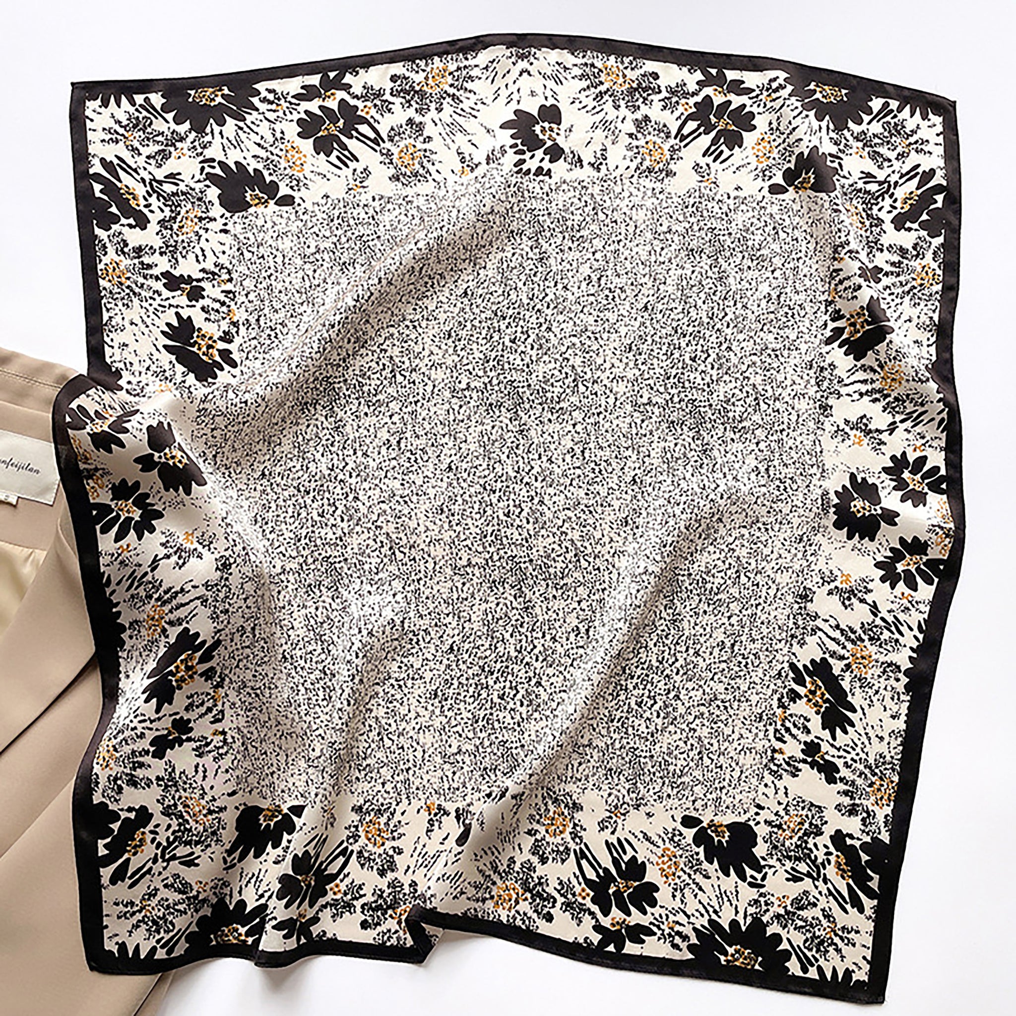 a women's black floral print silk square scarf on light beige base with black edges