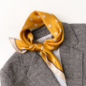 a mustard yellow small silk scarf/neckerchief with polka dot pattern