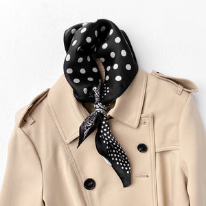 a black silk scarf neckerchief featuring paisley and polka dots pattern, knotted as a neck scarf, paired with a khaki coat