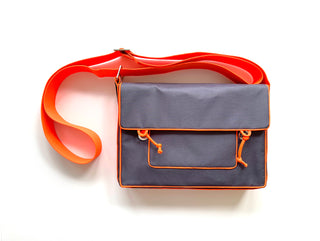 a grey preppy style messenger bag with orange strap