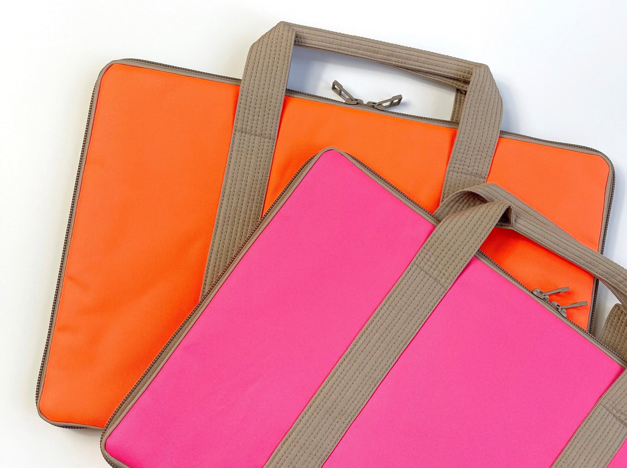 two laptop briefcases in bright pink and orange with beige straps, made of waterproof and recycled materials 