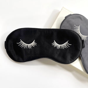 two silk eye masks featuring eyelashes embroidery and elastic strap in black and grey