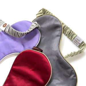 three professionally designed and handcrafted silk eye masks with elastic straps. One is purple with grey strap, one is grey with pea green strap and the third one is red with brown strap