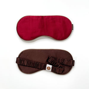 a red silk eye mask with brown back side and elastic strap